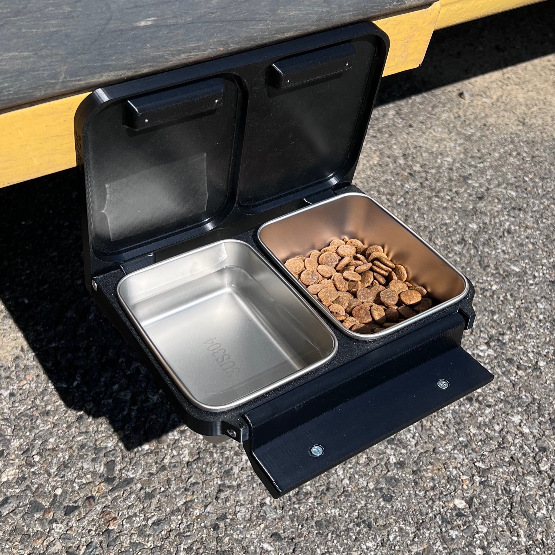 Support pour deux gamelles pour chien ou chat, aimanté sur la porte d'un van.